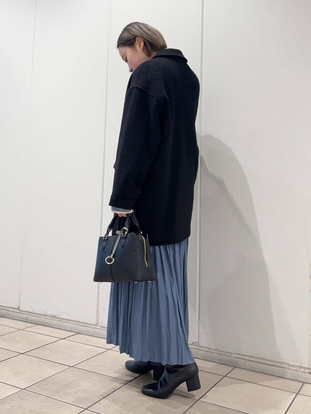 ブラック系のブーツ、ブラック系のその他アウター、ブルー系のスカートを着用したレディースの冬コーディネートの2枚目の写真