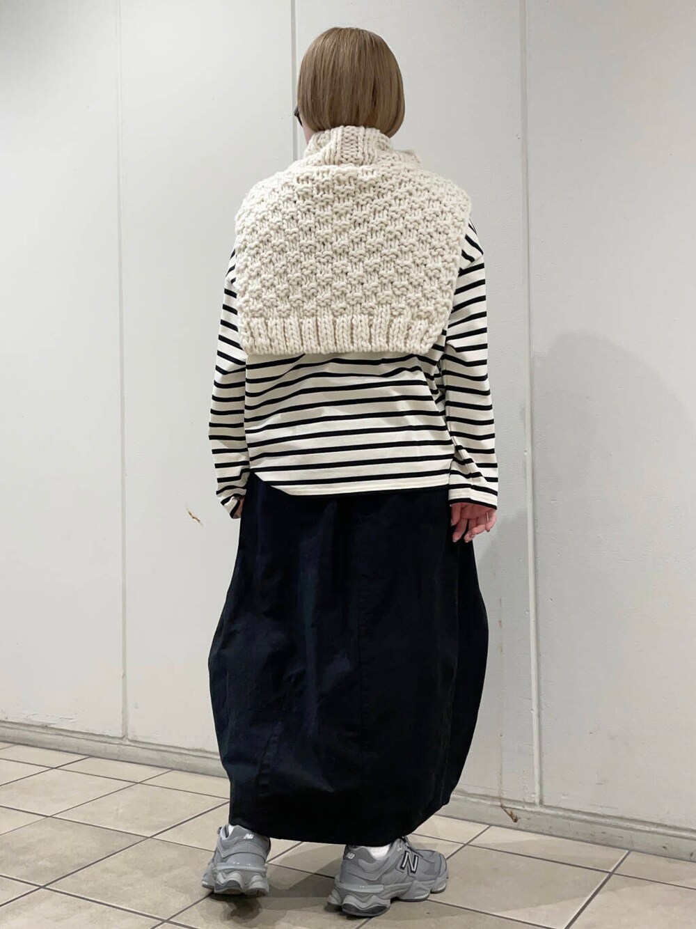 ホワイト系のTシャツ/カットソー、ブラック系のスカート、ホワイト系のネックウォーマー/スヌードを着用したレディースの冬コーディネートの5枚目の写真