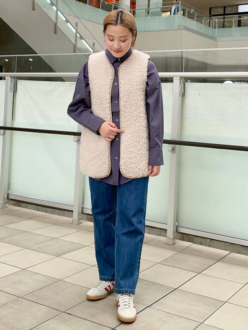 ブルー系のデニムパンツ、ベージュ系のベスト、ブルー系のシャツ/ブラウスを着用したレディースの秋コーディネートの3枚目の写真