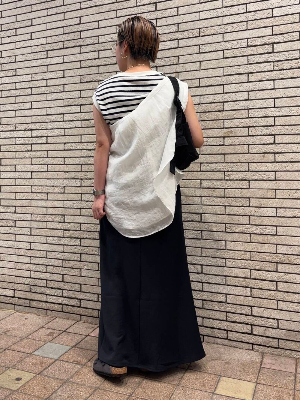 ブラック系のショルダーバッグ、グレー系のサンダル、ホワイト系のTシャツ/カットソーを着用したレディースの夏コーディネートの3枚目の写真