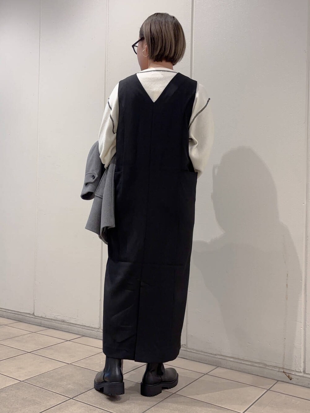 グレー系のその他アウター、ブラック系のブーツ、ホワイト系のニット/セーターを着用したレディースの冬コーディネートの3枚目の写真