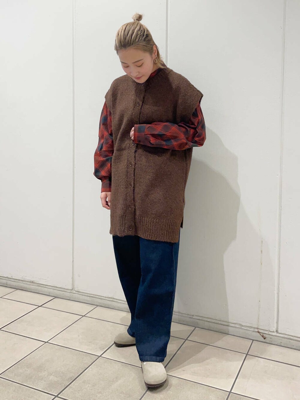 レッド系のシャツ/ブラウス、ブルー系のデニムパンツ、ブラウン系のベストを着用したレディースの秋コーディネートの2枚目の写真