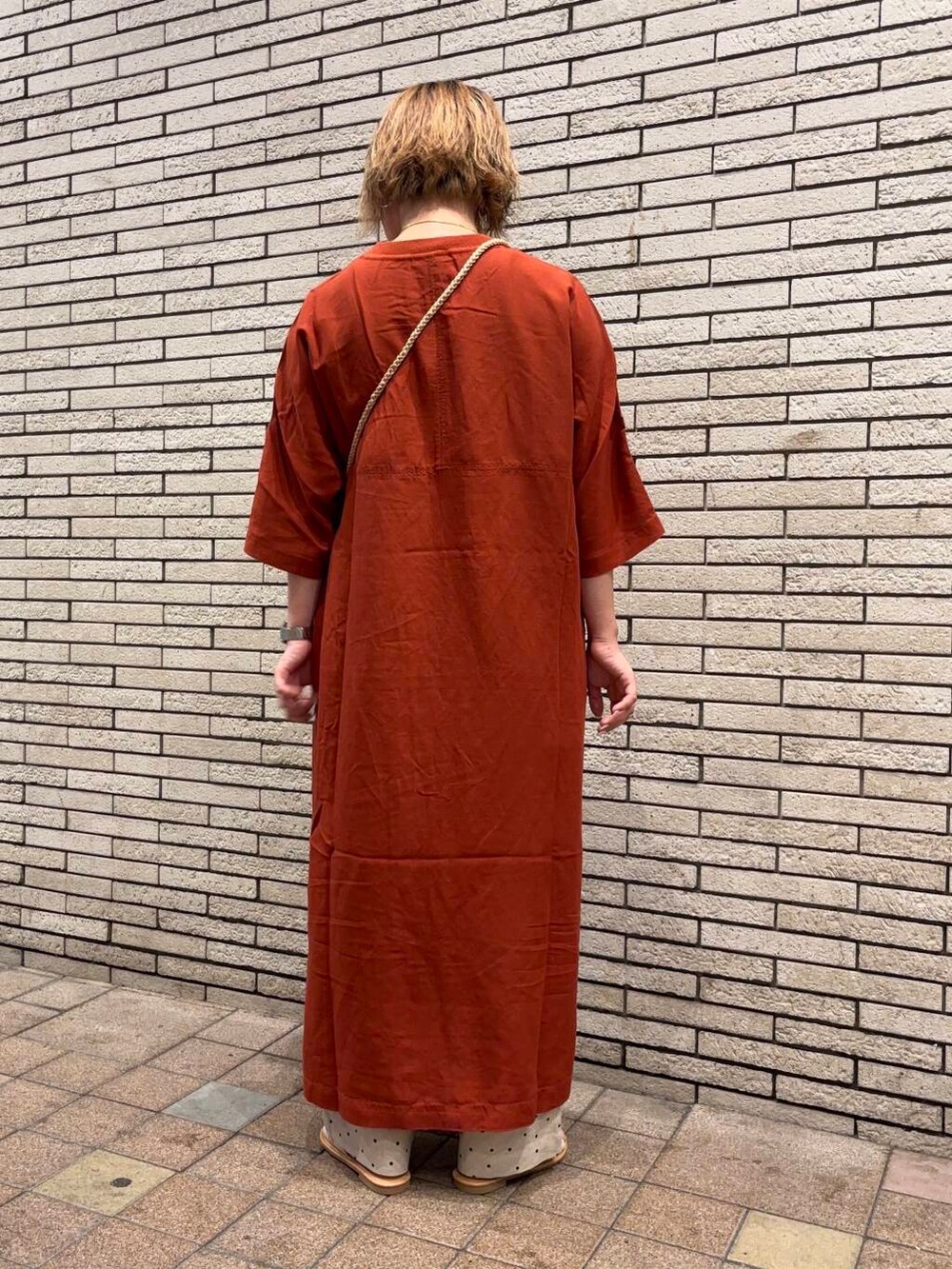 ブラック系のハンドバッグ、オレンジ系のワンピース、ホワイト系のサンダルを着用したレディースの春コーディネートの4枚目の写真