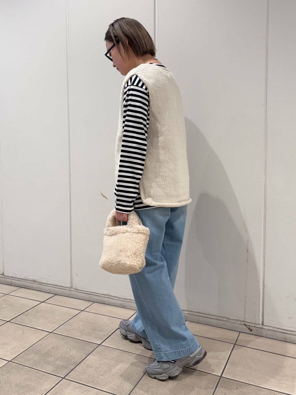 ホワイト系のニット/セーター、ベージュ系のハンドバッグ、ブラック系のTシャツ/カットソーを着用したレディースの冬コーディネートの2枚目の写真