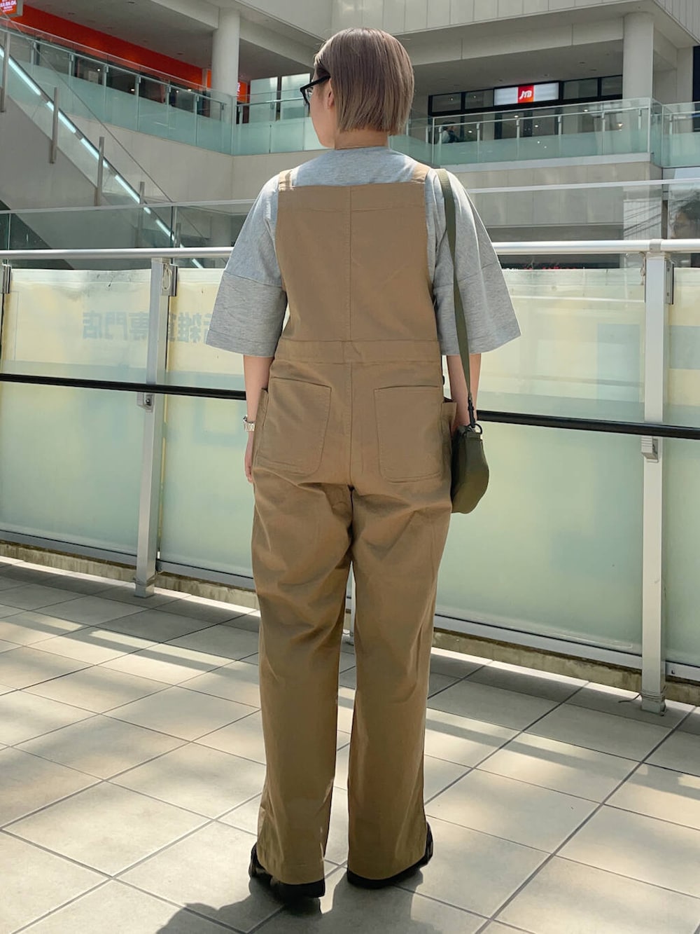 グリーン系のショルダーバッグ、イエロー系のサロペット/オーバーオール、グレー系のTシャツ/カットソーを着用したレディースの夏コーディネートの3枚目の写真