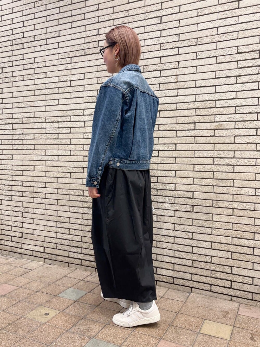 ブルー系のデニムジャケット、ブラック系のスカート、ホワイト系のスニーカーを着用したレディースの春コーディネートの3枚目の写真