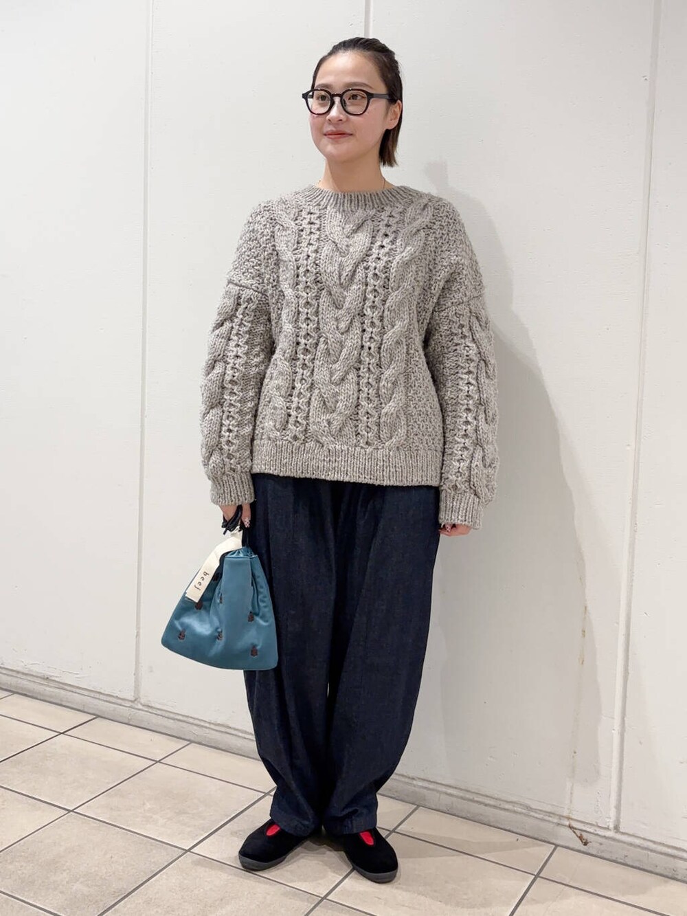 グレー系のニット/セーター、ブルー系のショルダーバッグ、ブルー系のデニムパンツを着用したレディースの冬コーディネートの4枚目の写真
