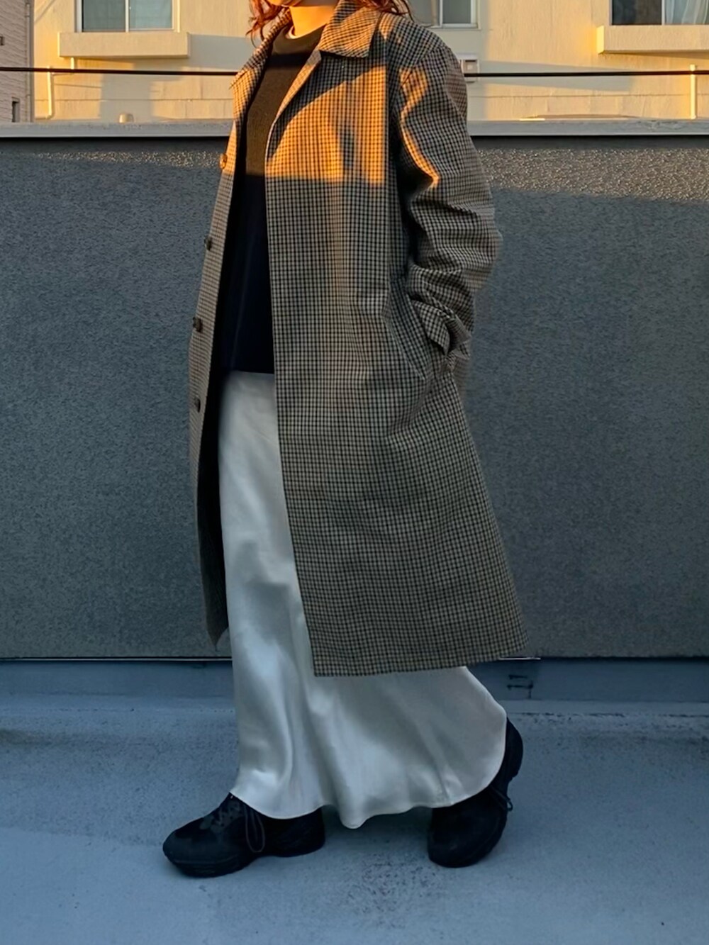 ホワイト系のスカート、ブラック系のスニーカー、ブラウン系のステンカラーコートを着用したレディースの冬コーディネートの2枚目の写真