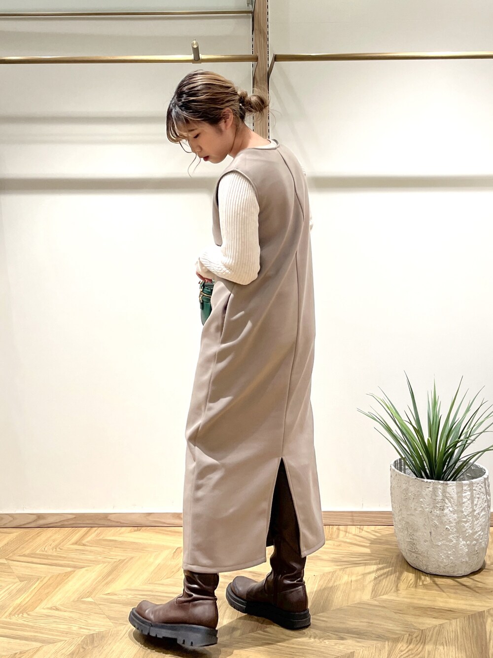 ホワイト系のニット/セーター、ブラウン系のワンピース、グリーン系のショルダーバッグを着用したレディースの春コーディネートの2枚目の写真