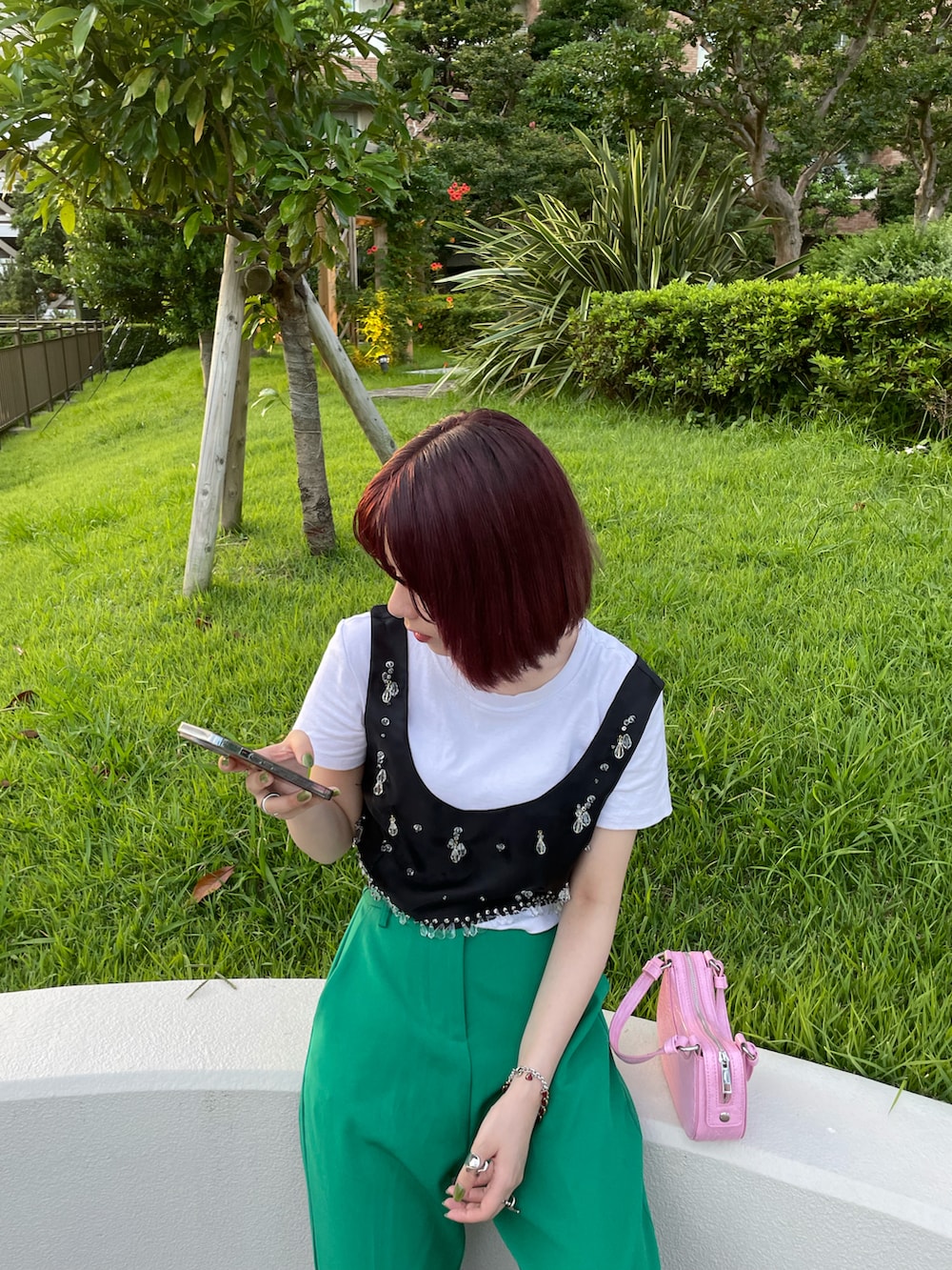 グリーン系のスラックス、ブラック系のサンダル、ホワイト系のトップスを着用したレディースの夏コーディネートの2枚目の写真