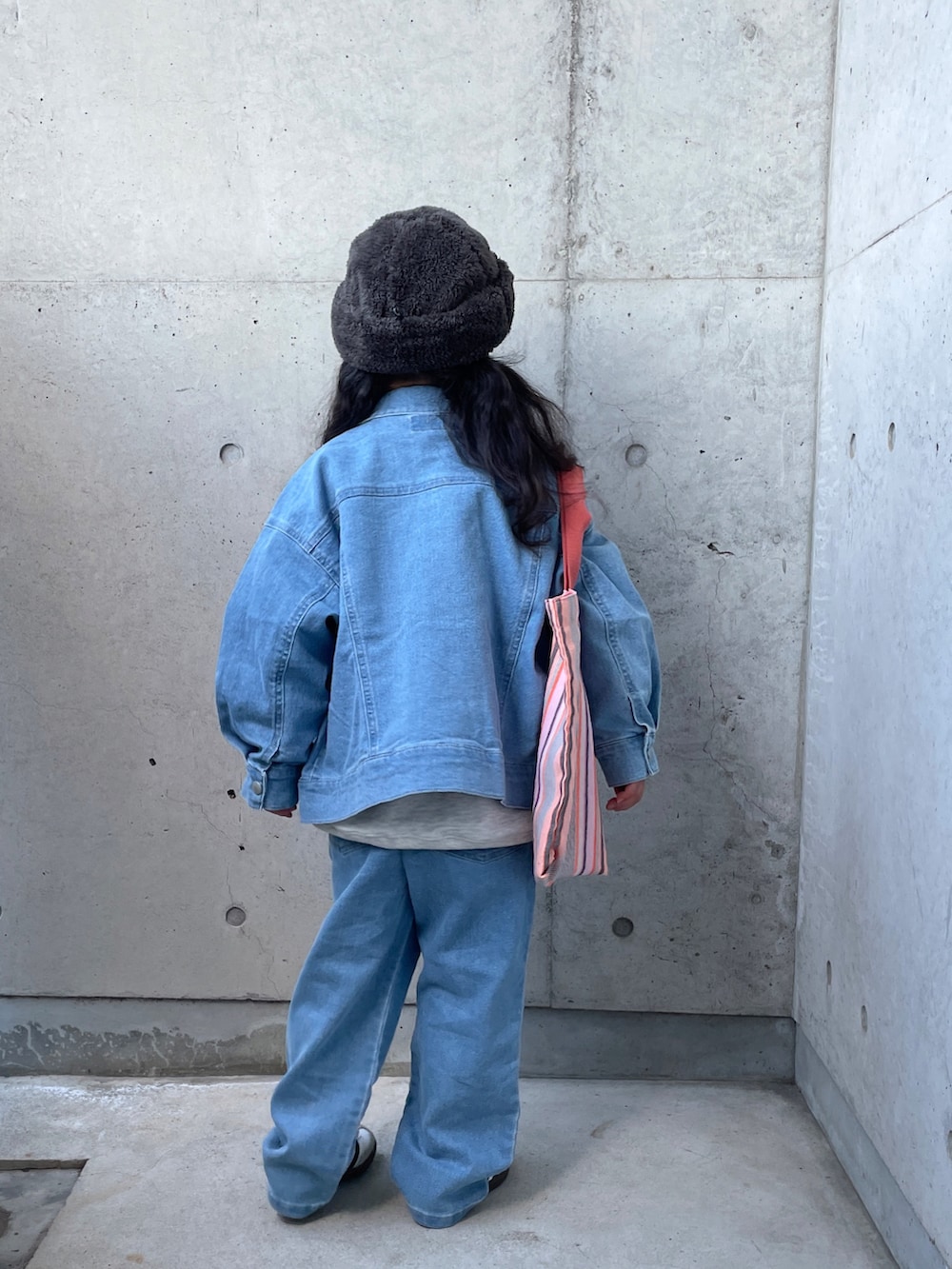 ブルー系のデニムジャケット、オレンジ系のトートバッグ、グレー系のスウェットを着用したキッズの冬コーディネートの3枚目の写真