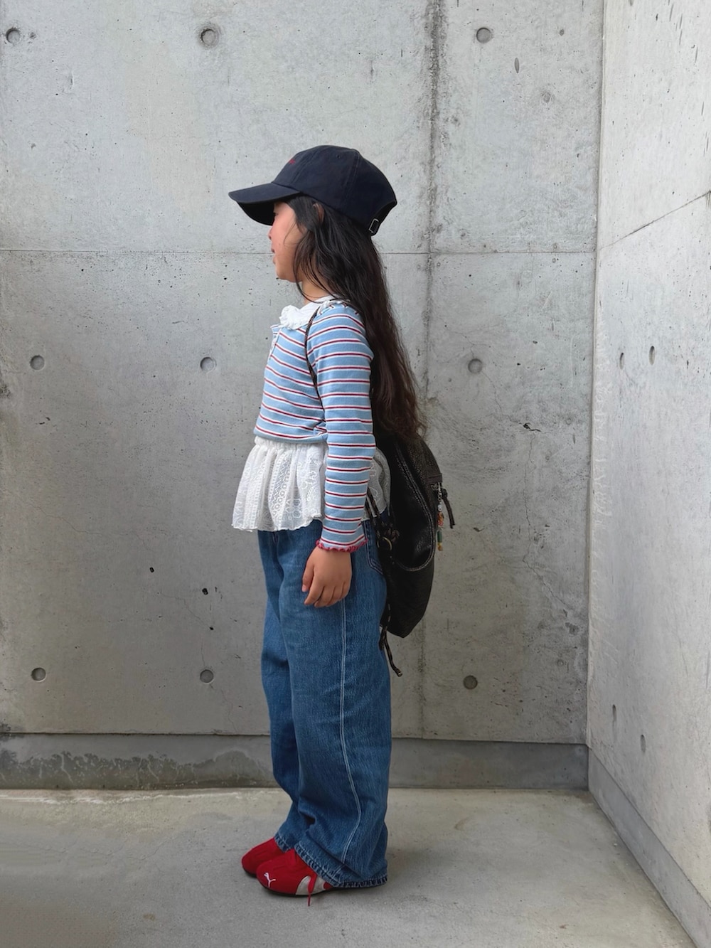 ブラック系のスカート、レッド系のスニーカー、ブラック系のバックパック/リュックを着用したキッズの春コーディネートの2枚目の写真