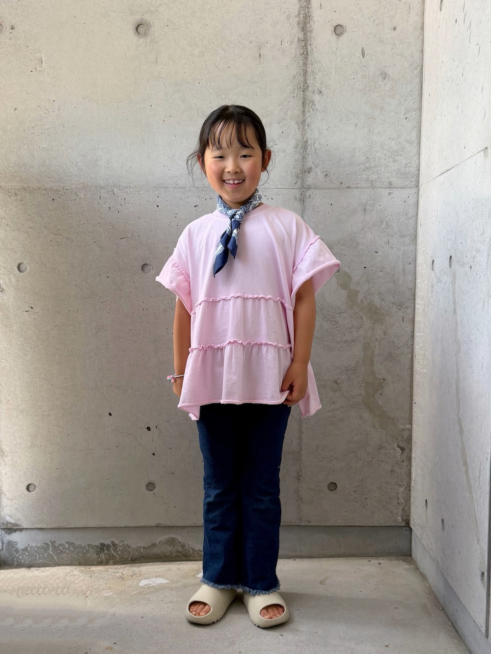 ピンク系のTシャツ/カットソー、ベージュ系のサンダル、ブルー系のデニムパンツを着用したキッズの夏コーディネートの3枚目の写真