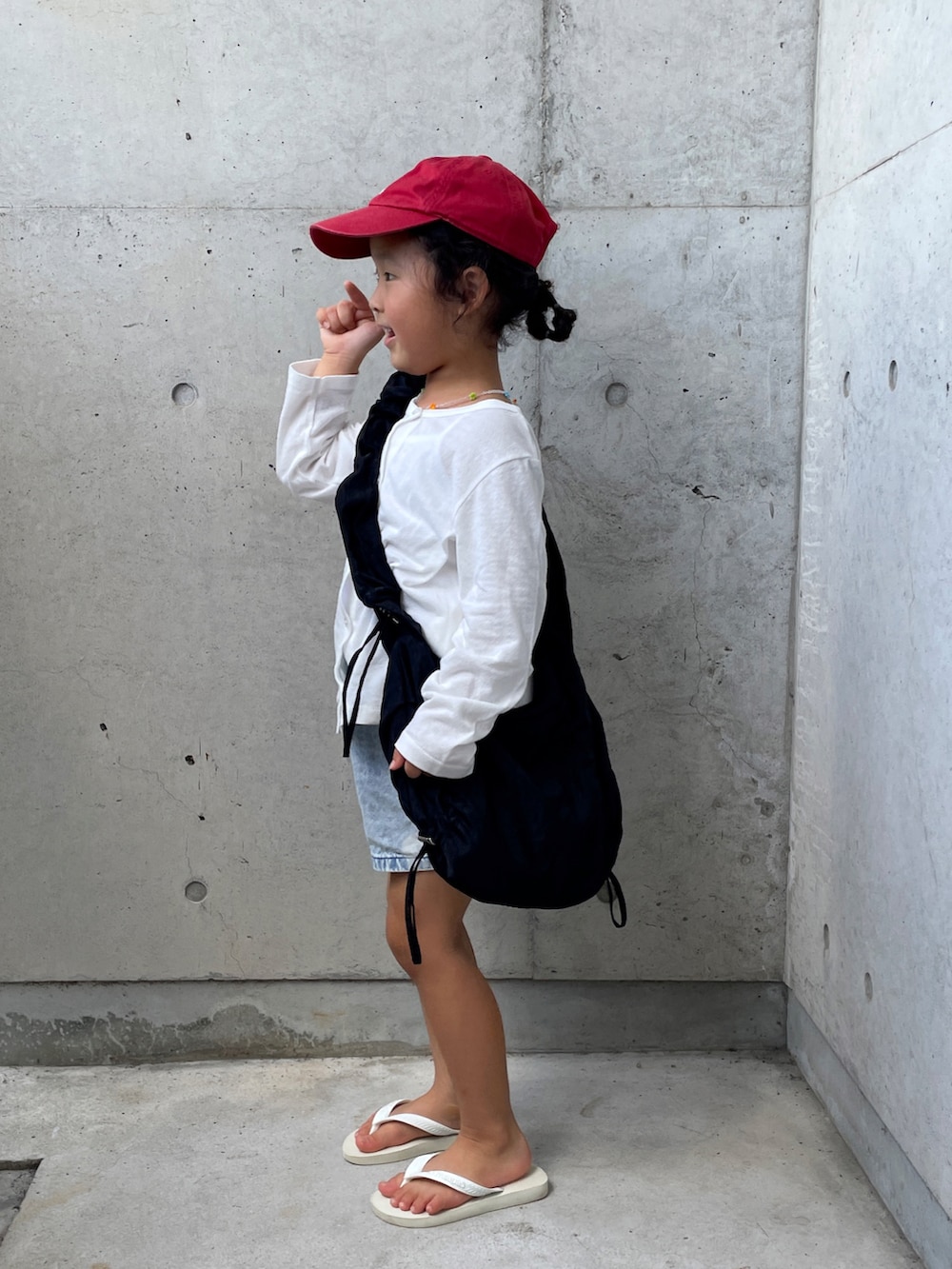 ブラック系のショルダーバッグ、ブルー系のデニムパンツ、ホワイト系のサンダルを着用したキッズの夏コーディネートの2枚目の写真