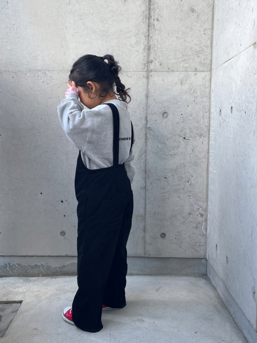 グレー系のスウェット、ブラック系のサロペット/オーバーオール、ピンク系のニット/セーターを着用したキッズの冬コーディネートの4枚目の写真