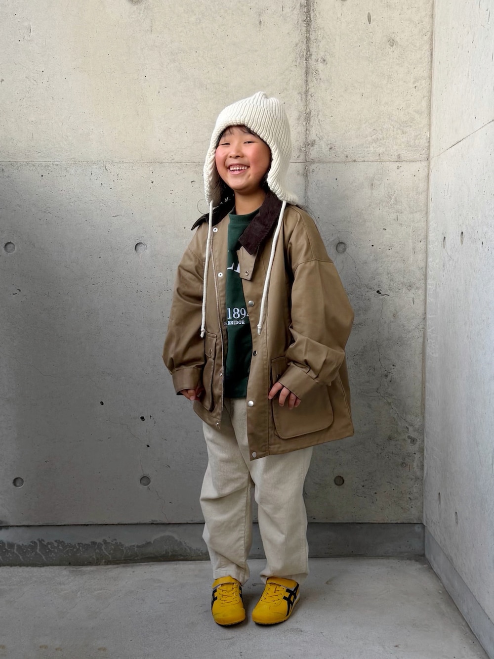ベージュ系のミリタリージャケット、ベージュ系のその他パンツ、イエロー系のスニーカーを着用したキッズの秋コーディネートの4枚目の写真