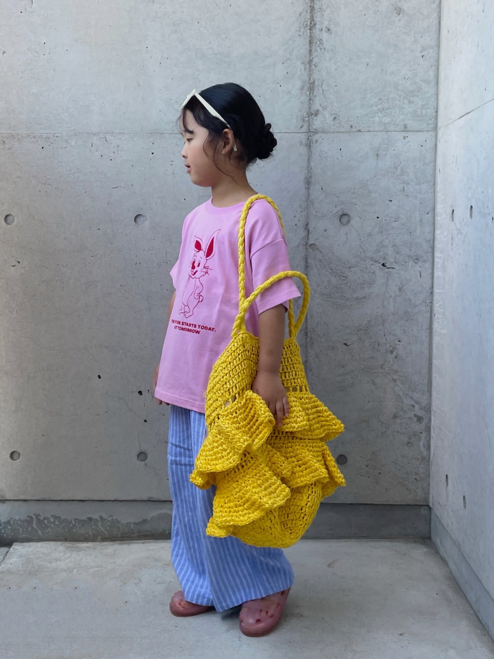 ピンク系のTシャツ/カットソー、ブルー系のパンツ、イエロー系のかごバッグを着用したキッズの夏コーディネートの2枚目の写真