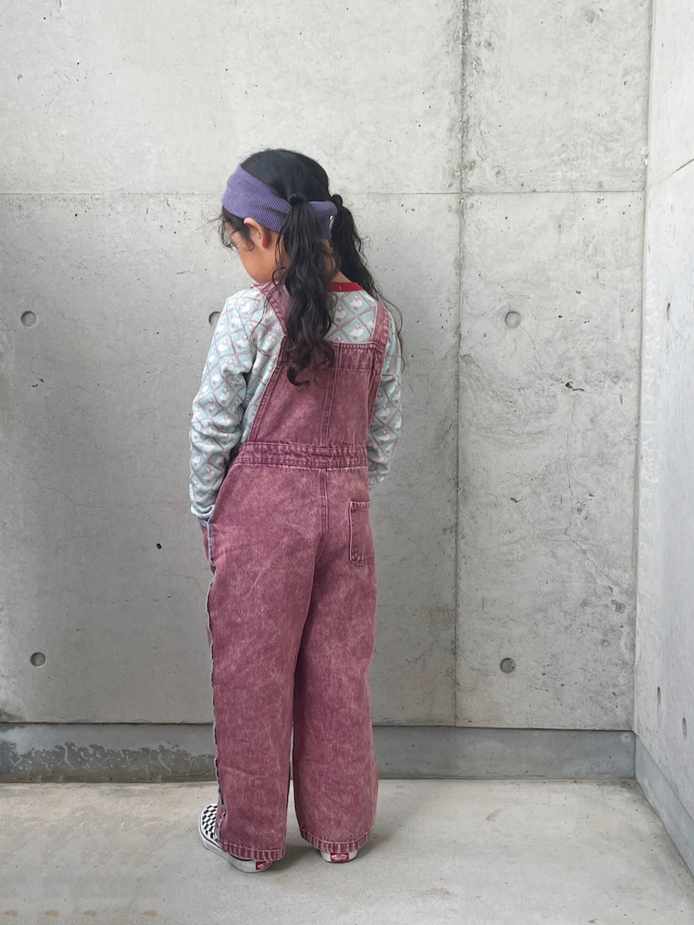 ブラック系のスリッポン、ブルー系のトップス、レッド系のサロペット/オーバーオールを着用したキッズの秋コーディネートの4枚目の写真