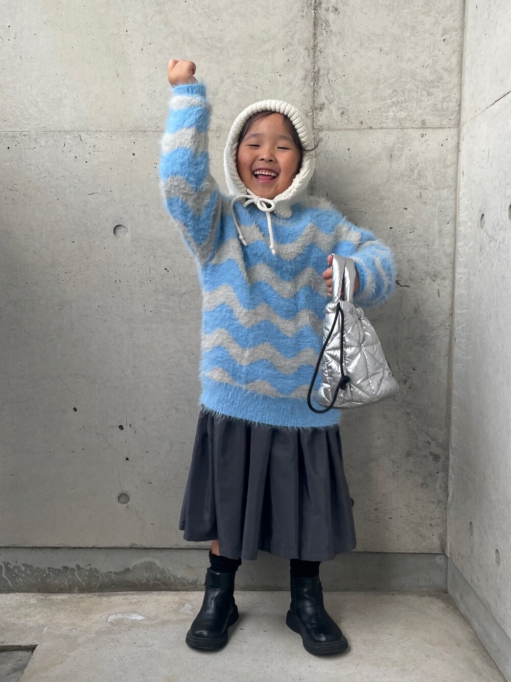 ブルー系のニット/セーター、グレー系のワンピース、シルバー系のトートバッグを着用したキッズの秋コーディネートの4枚目の写真