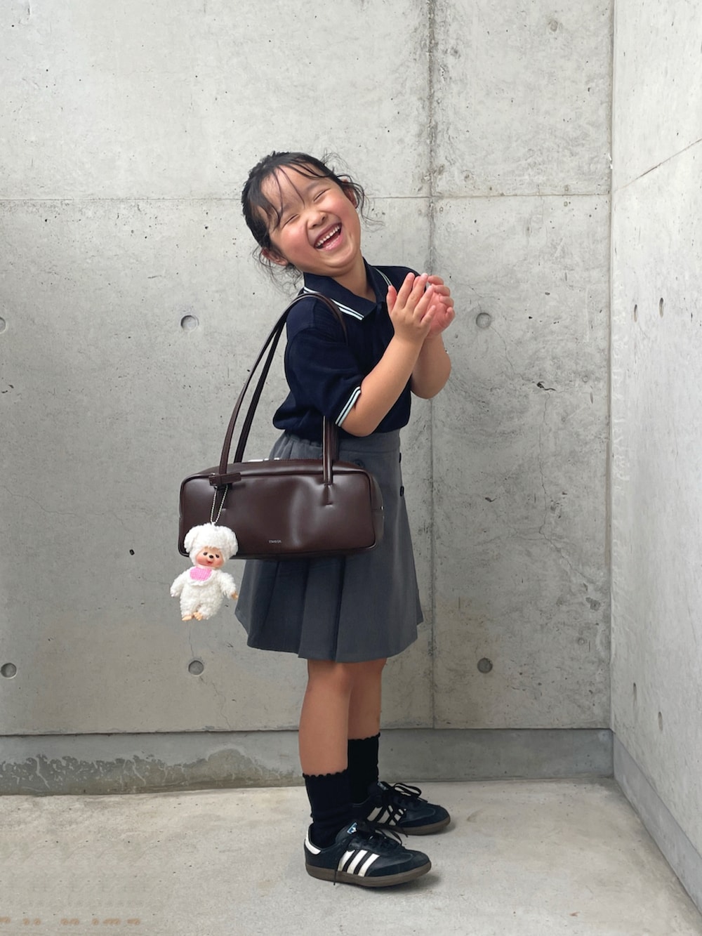 ブラック系のスニーカー、ブルー系のポロシャツ、ブラウン系のショルダーバッグを着用したキッズの秋コーディネートの2枚目の写真