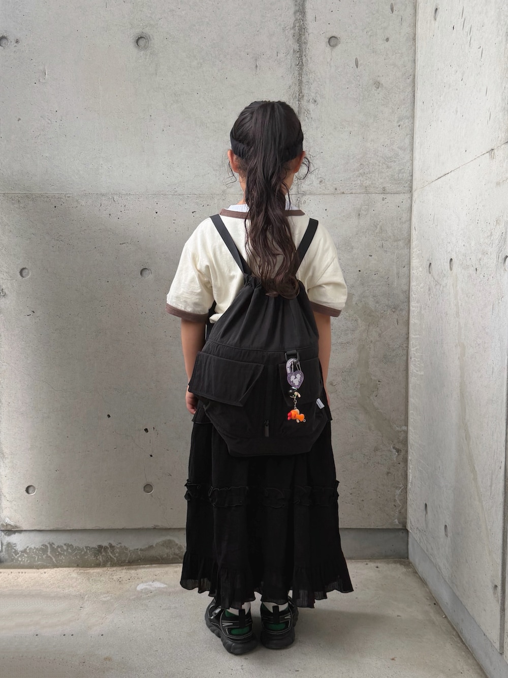 ホワイト系のTシャツ/カットソー、ブラック系のスカート、ブラック系のバックパック/リュックを着用したキッズの夏コーディネートの3枚目の写真