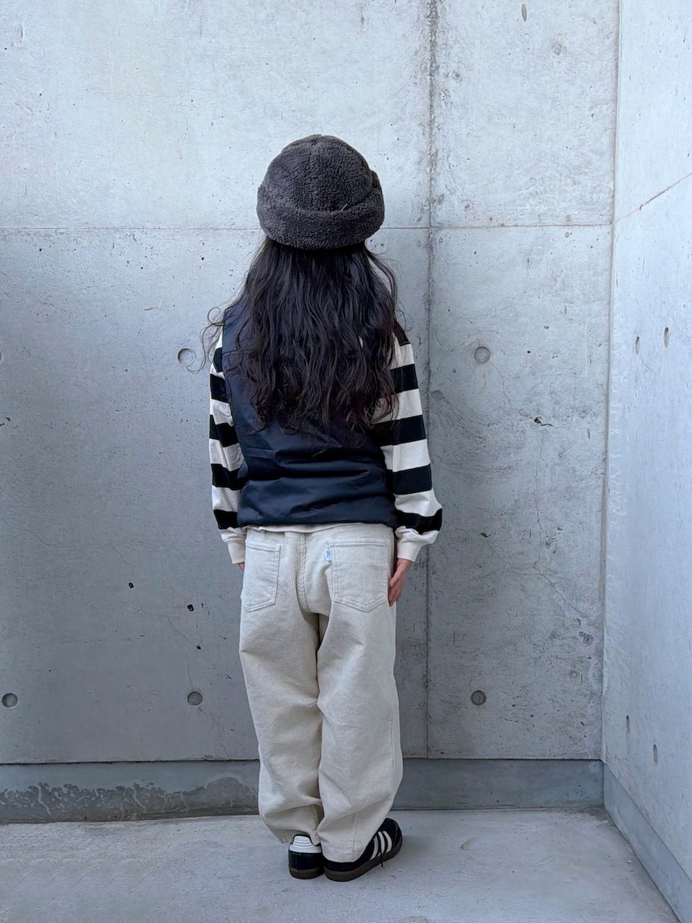 ベージュ系のその他パンツ、ブラック系のスニーカー、ブラック系のベストを着用したキッズの秋コーディネートの3枚目の写真