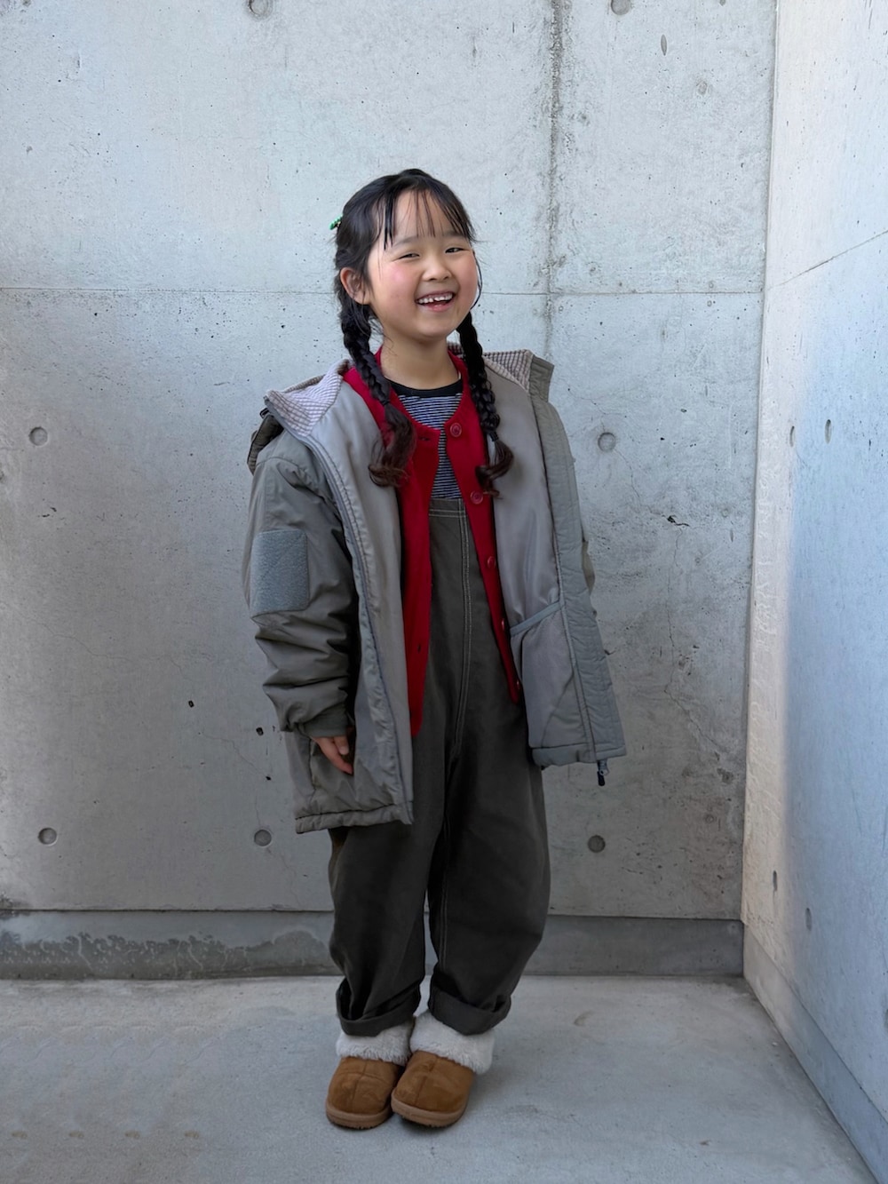 グレー系のサロペット/オーバーオール、ブラウン系のブーツ、ブラック系のTシャツ/カットソーを着用したキッズの冬コーディネートの3枚目の写真