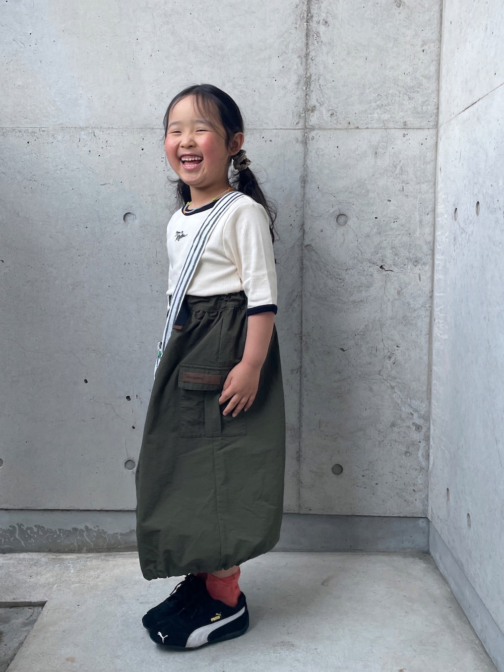 ホワイト系のTシャツ/カットソー、グリーン系のスカート、ブラック系のスニーカーを着用したキッズの春コーディネートの5枚目の写真