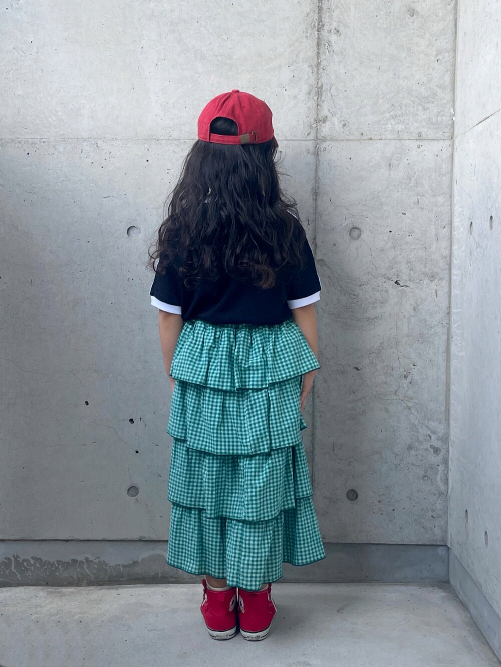 ブラック系のTシャツ/カットソー、レッド系のスニーカー、グリーン系のスカートを着用したキッズの秋コーディネートの5枚目の写真