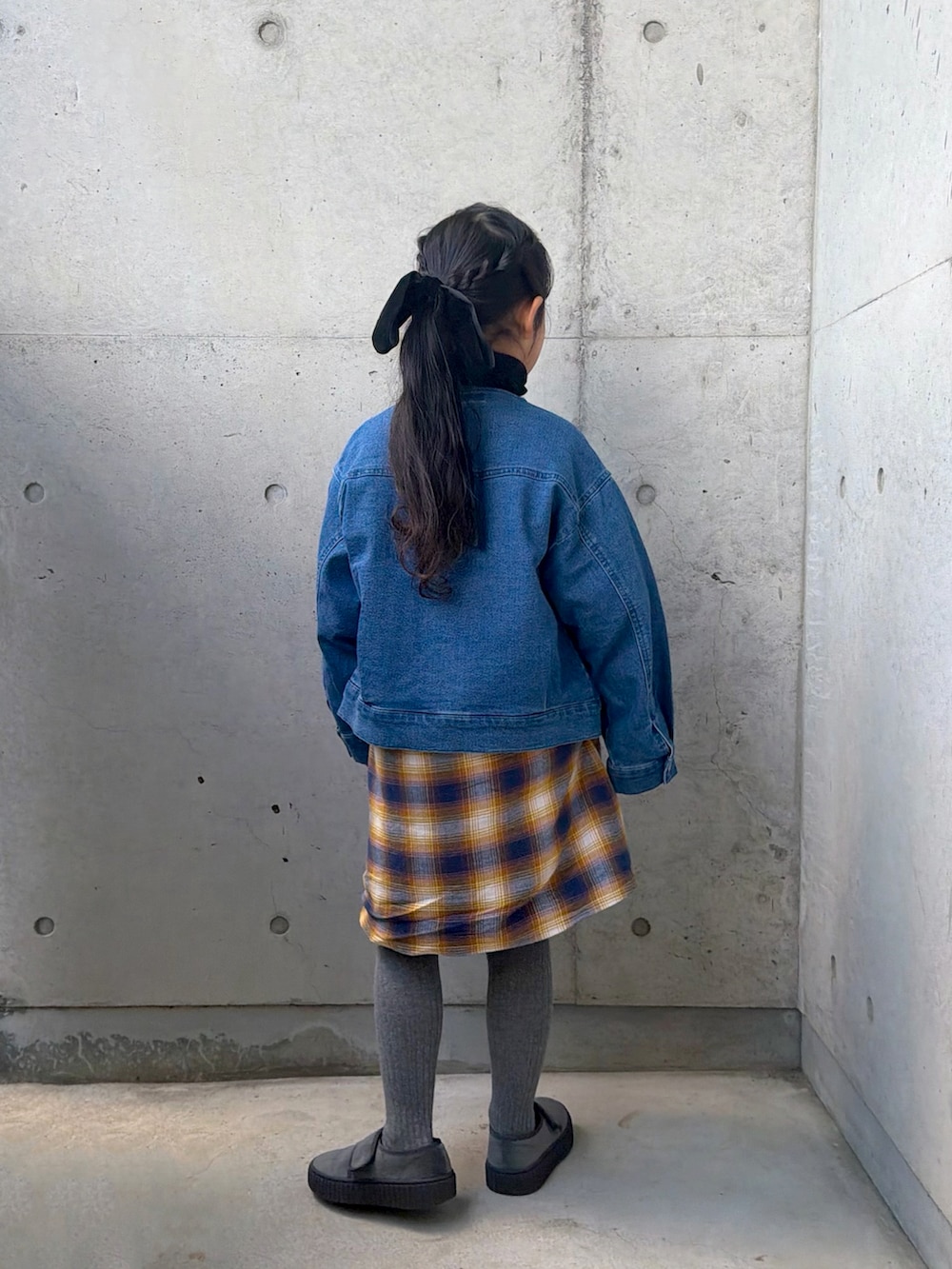イエロー系のワンピース、グレー系のその他シューズ、ブラック系のニット/セーターを着用したキッズの冬コーディネートの3枚目の写真