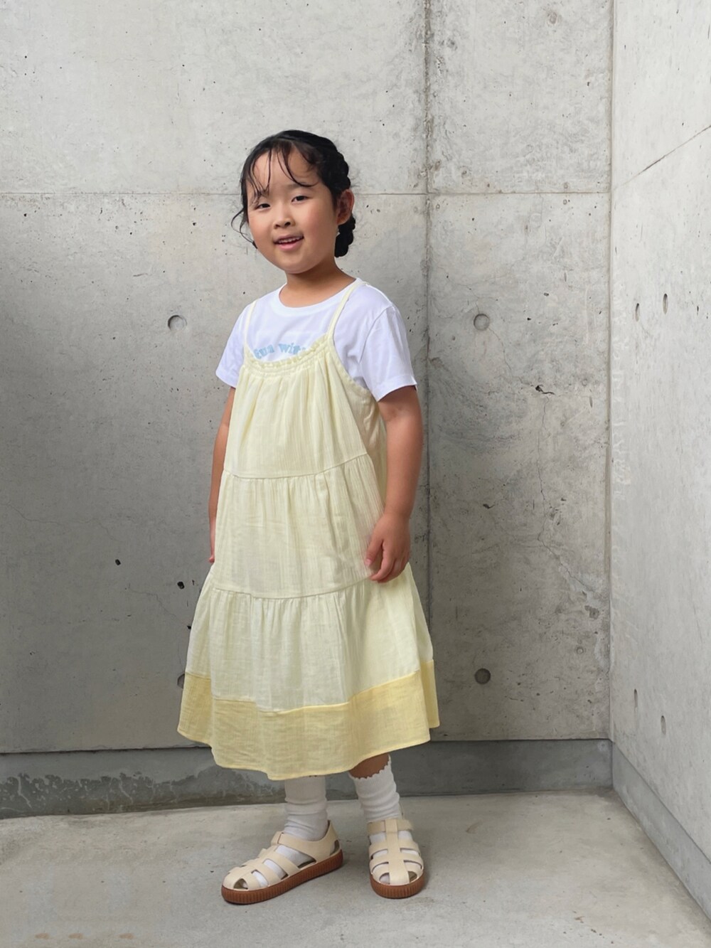 ホワイト系のサンダル、ホワイト系のTシャツ/カットソー、イエロー系のワンピースを着用したキッズの夏コーディネートの4枚目の写真
