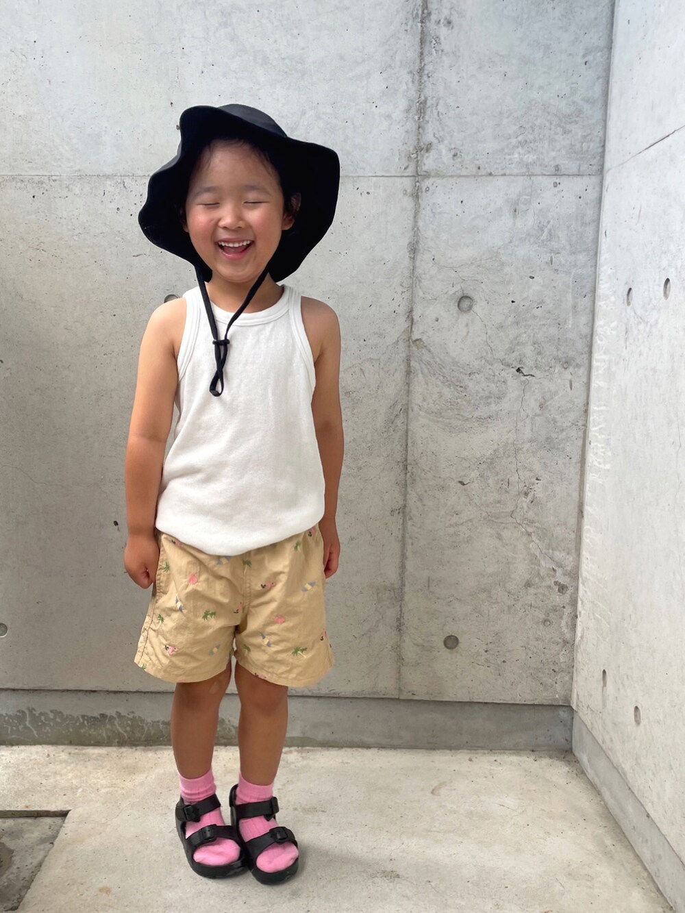 ホワイト系のタンクトップ、ベージュ系のパンツ、ブラック系のサンダルを着用したキッズの夏コーディネートの4枚目の写真