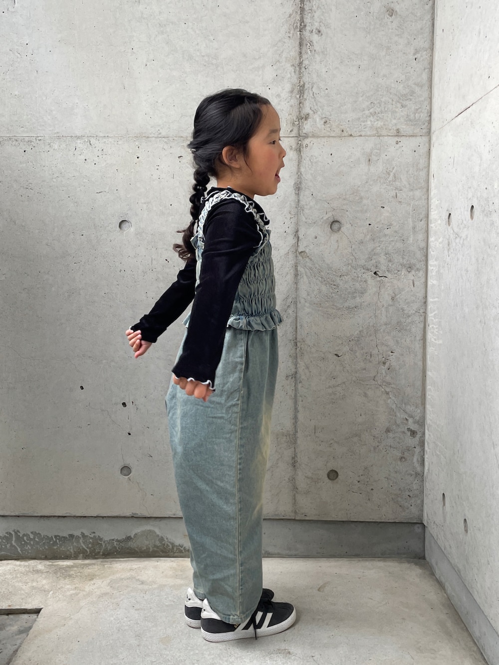 ブラック系のTシャツ/カットソー、ブルー系のオールインワン・サロペット、ブラック系のスニーカーを着用したキッズの春コーディネートの2枚目の写真