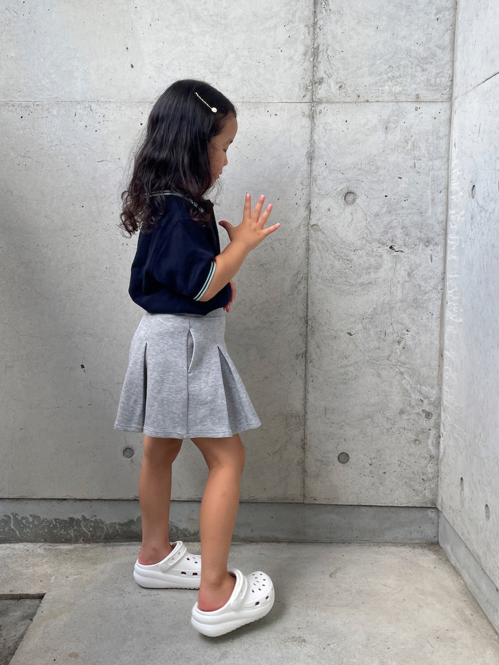ホワイト系のサンダル、ブルー系のポロシャツ、グレー系のスカートを着用したキッズの夏コーディネートの2枚目の写真