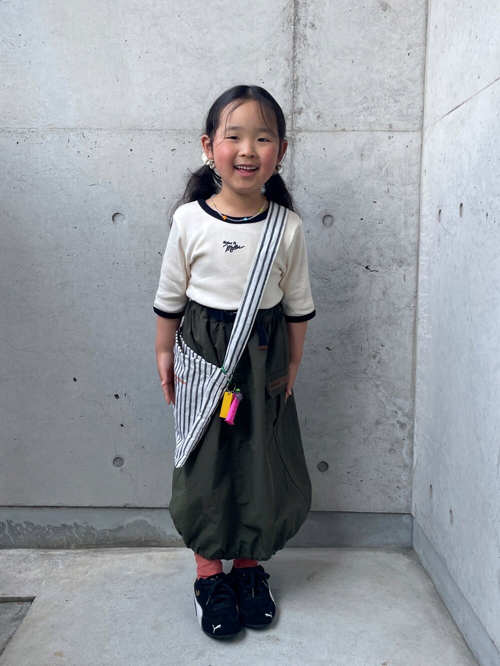 ホワイト系のTシャツ/カットソー、グリーン系のスカート、ブラック系のスニーカーを着用したキッズの春コーディネートの3枚目の写真
