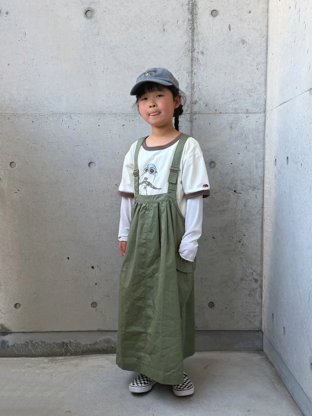 ブラック系のスリッポン、グリーン系のジャンパースカート、ホワイト系のTシャツ/カットソーを着用したキッズの春コーディネートの4枚目の写真