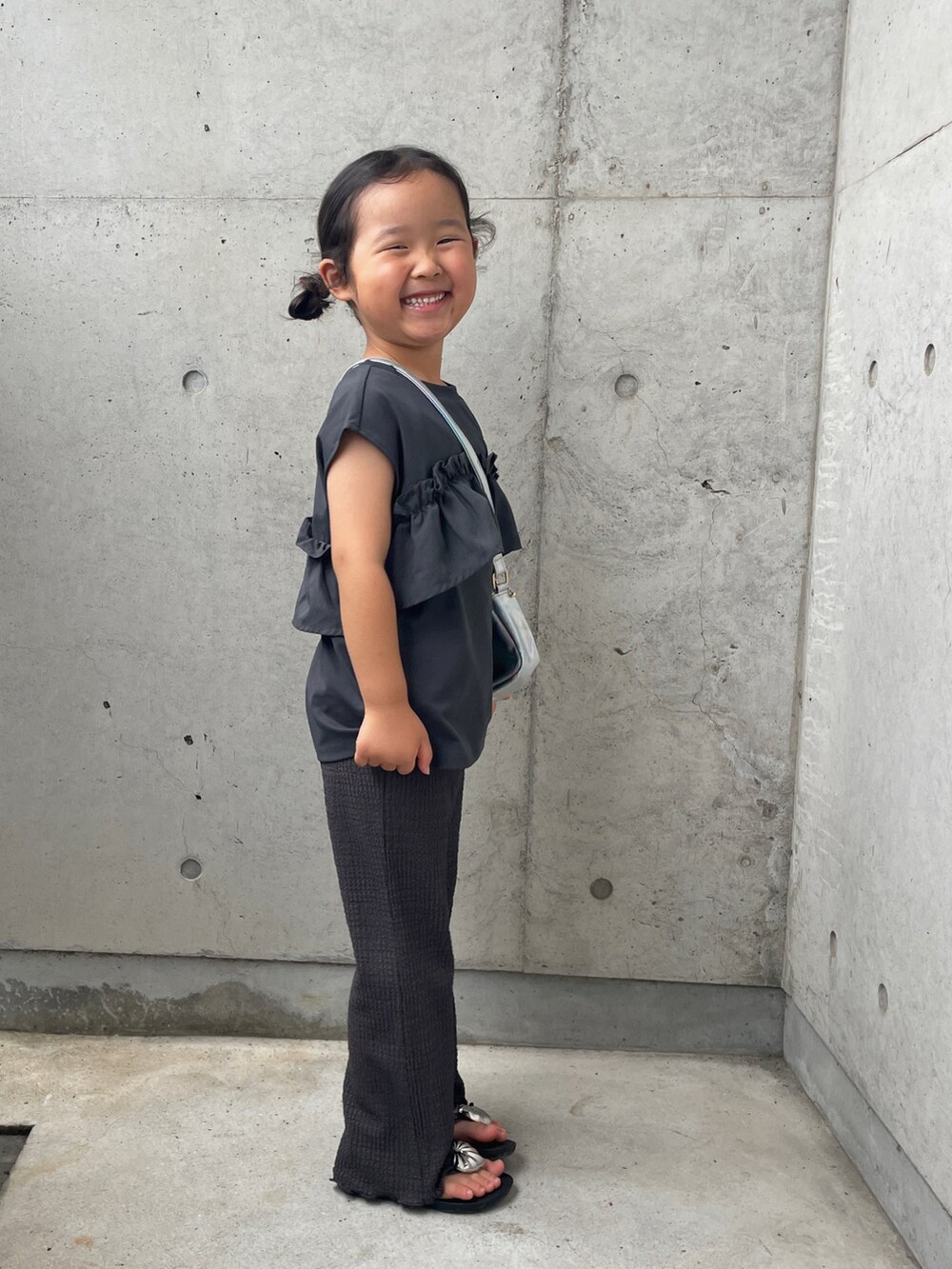 グレー系のタンクトップ、シルバー系のショルダーバッグ、グレー系のその他パンツを着用したキッズの夏コーディネートの2枚目の写真