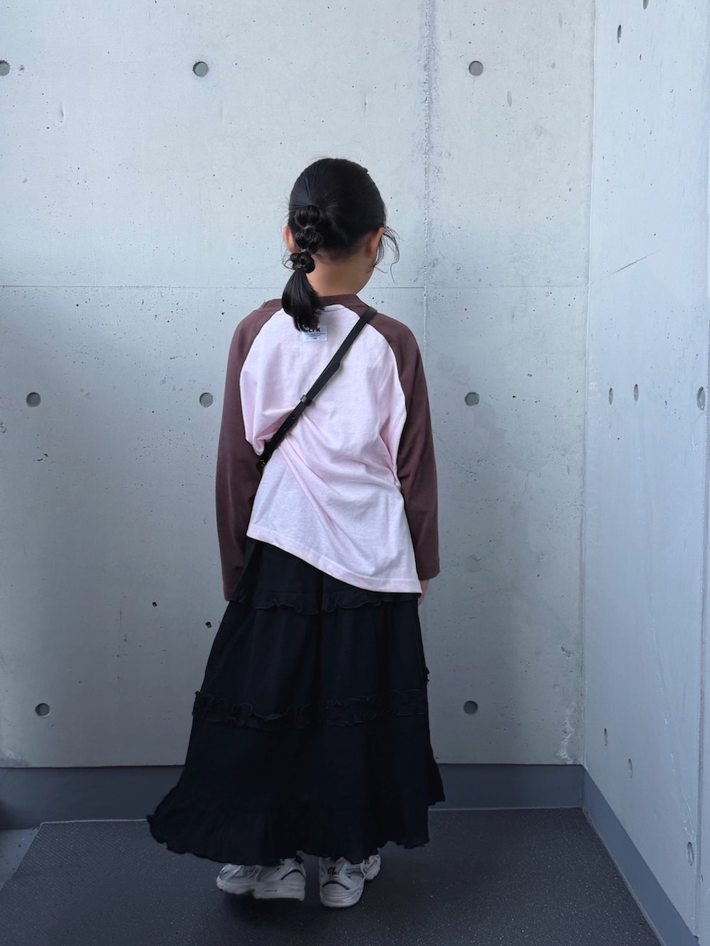 ホワイト系のスニーカー、ピンク系のTシャツ/カットソー、ブラック系のスカートを着用したキッズの秋コーディネートの4枚目の写真