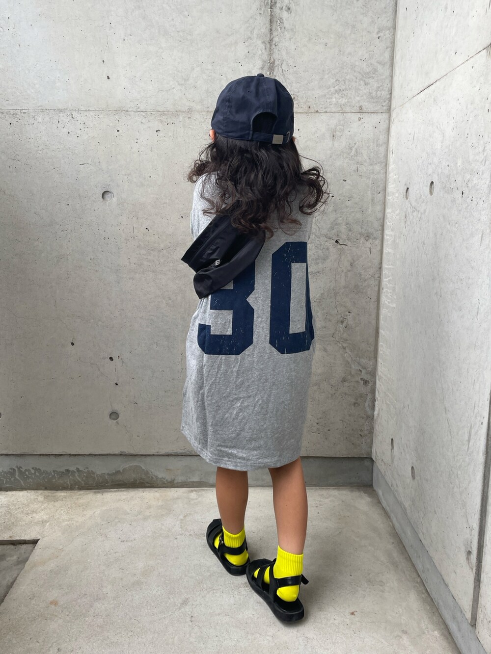 グレー系のワンピース、ブラック系のサンダル、ブルー系のキャップを着用したキッズの夏コーディネートの5枚目の写真