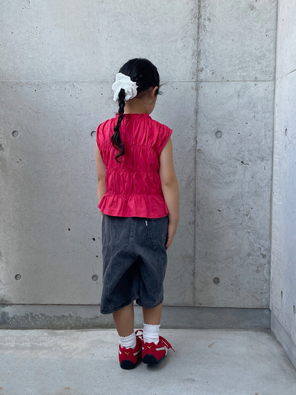 ブラック系のデニムパンツ、レッド系のスニーカー、レッド系のトップスを着用したキッズの夏コーディネートの3枚目の写真