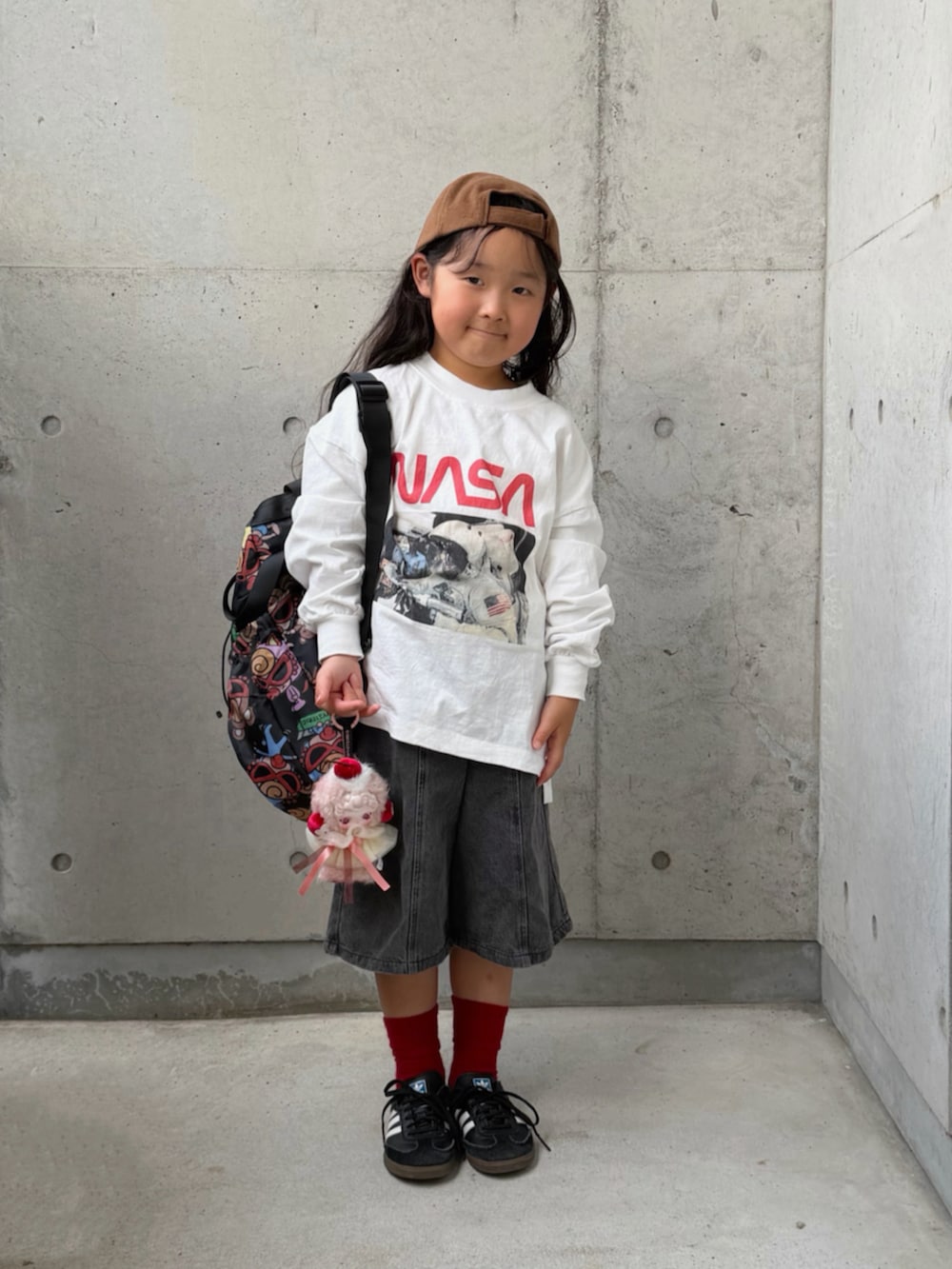 ブラック系のスニーカー、ホワイト系のTシャツ/カットソー、ブラック系のデニムパンツを着用したキッズの秋コーディネートの3枚目の写真