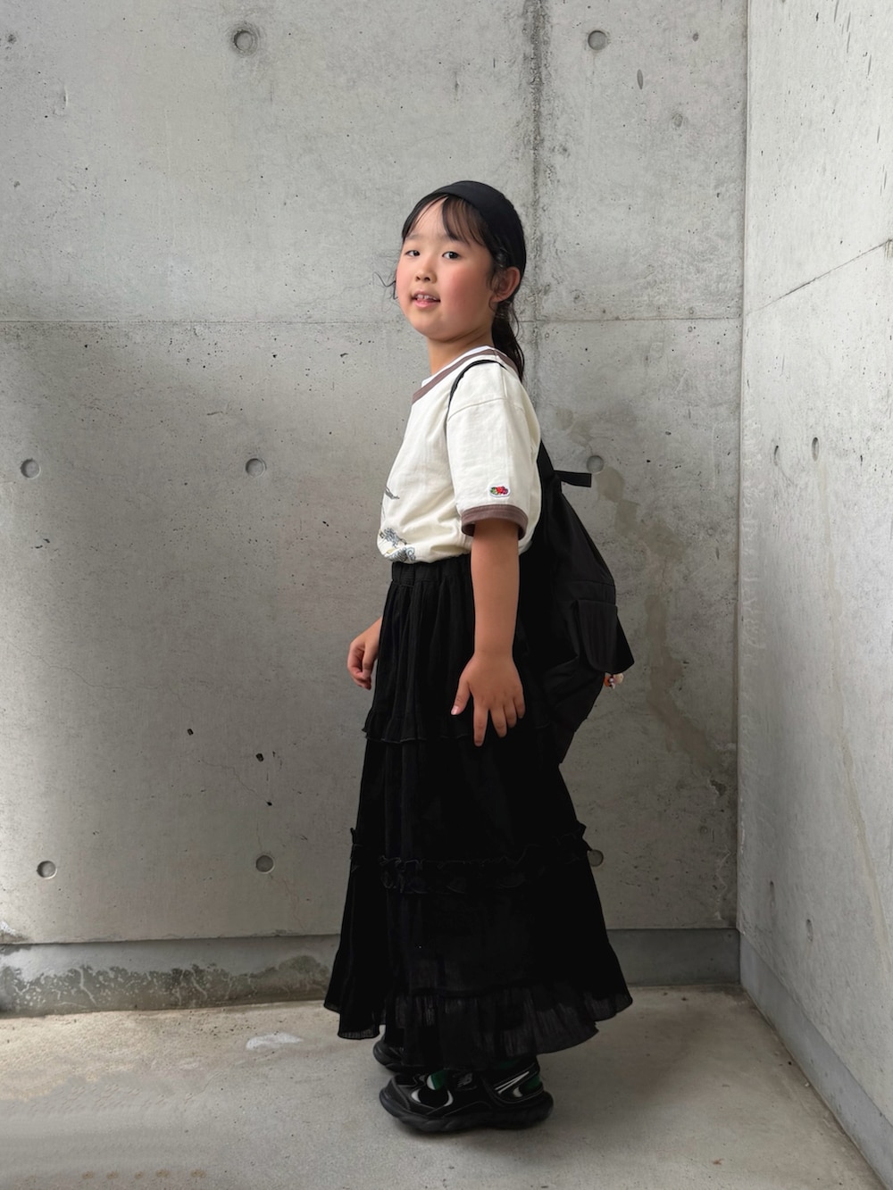 ホワイト系のTシャツ/カットソー、ブラック系のスカート、ブラック系のバックパック/リュックを着用したキッズの夏コーディネートの2枚目の写真