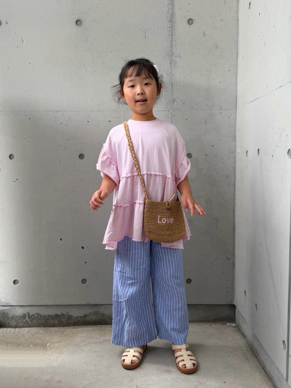 ピンク系のTシャツ/カットソー、ベージュ系のショルダーバッグ、ホワイト系のサンダルを着用したキッズの夏コーディネートの5枚目の写真