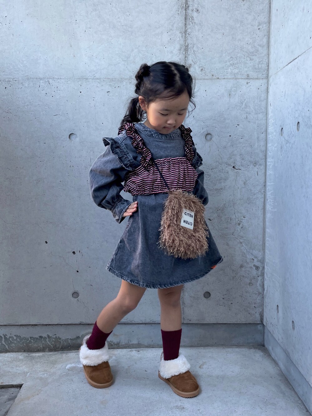 ブラウン系のショルダーバッグ、レッド系のキャミソール、ブラウン系のブーツを着用したキッズの秋コーディネートの2枚目の写真