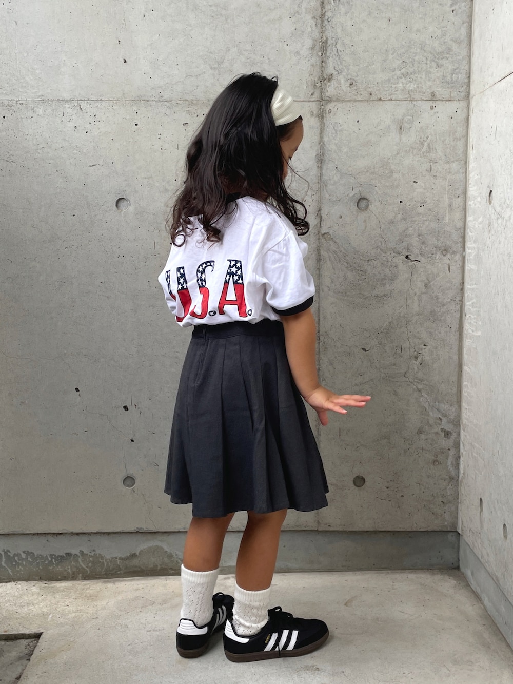 グレー系のスカート、ホワイト系のTシャツ/カットソー、ブラック系のスニーカーを着用したキッズの夏コーディネートの4枚目の写真