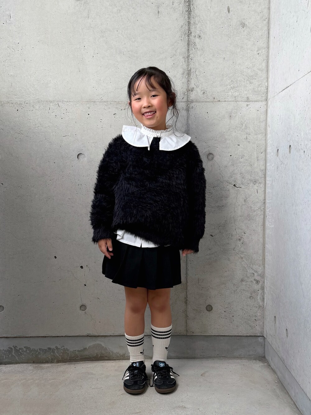 ブラック系のニット/セーター、ブラック系のスニーカー、ホワイト系のシャツ/ブラウスを着用したキッズの秋コーディネートの3枚目の写真