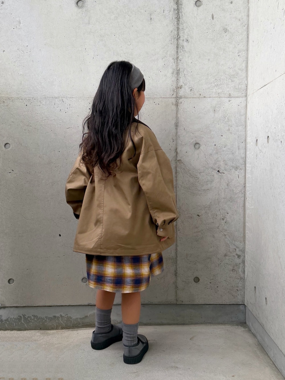 ベージュ系のミリタリージャケット、イエロー系のワンピース、グレー系のその他シューズを着用したキッズの冬コーディネートの3枚目の写真