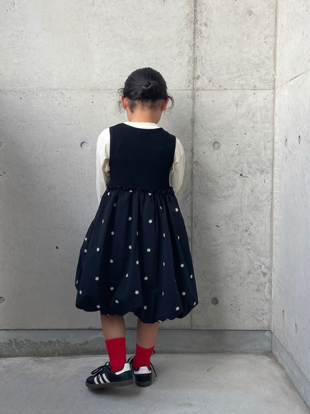 ブラック系のワンピース、ブラック系のスニーカー、ホワイト系のTシャツ/カットソーを着用したキッズの秋コーディネートの3枚目の写真