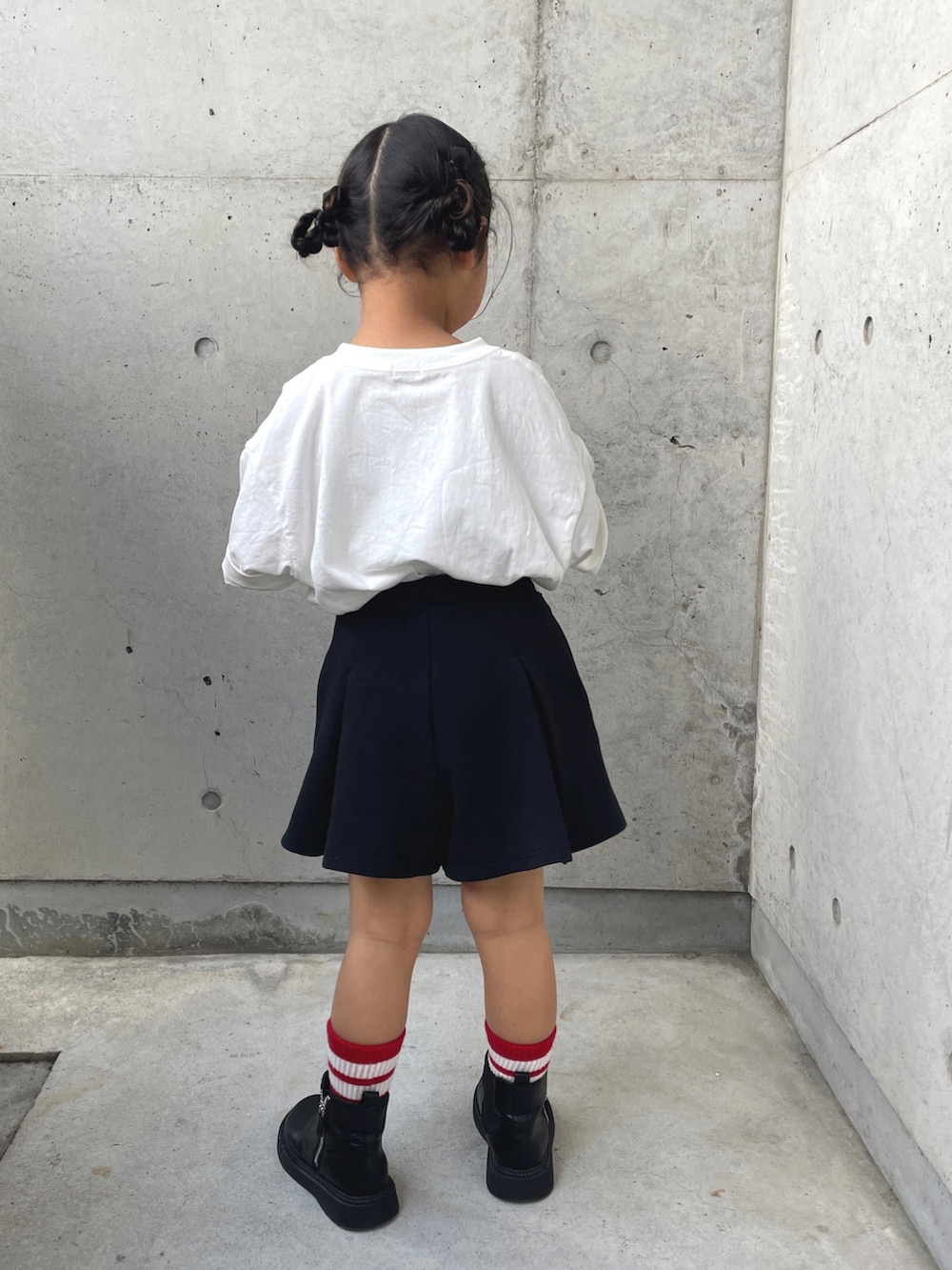 ホワイト系のTシャツ/カットソー、ブラック系のスカート、ブラック系のブーツを着用したキッズの春コーディネートの3枚目の写真