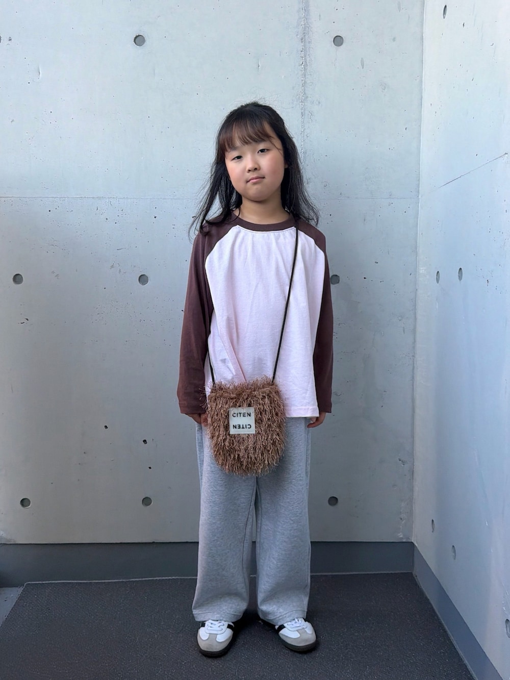 ピンク系のTシャツ/カットソー、ブラウン系のショルダーバッグ、ホワイト系のスニーカーを着用したキッズの秋コーディネートの3枚目の写真